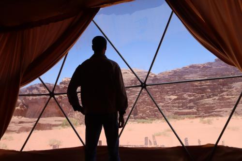 a man standing in a window looking out at the desert at Wadi rum Bubble Camp & tour in Wadi Rum