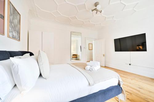 a white bedroom with a large bed and a flat screen tv at Huge 2 Bedrooms 3 Beds! Covent GDN 3 min to subway in London