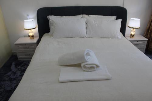 a white towel laying on a bed with two night stands at Ajman for families in Ajman 