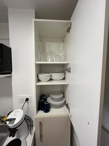 - une cuisine blanche avec des assiettes et de la vaisselle sur les étagères dans l'établissement Magnifique appartement renové le Victoria, à Aix-les-Bains