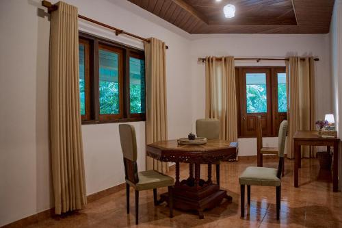 a dining room with a table and chairs and windows at Kandahena Mansion in Akuressa