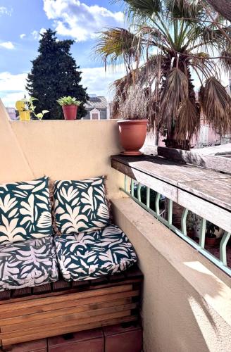 un banc avec des coussins sur un balcon avec des palmiers dans l'établissement Le Mourillon Grand appartement proche des plages, à Toulon
