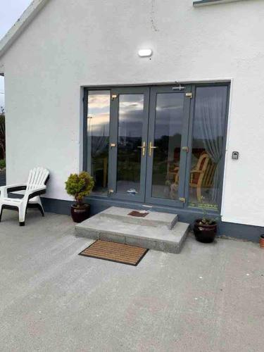 a patio with a white bench and a window at Tigh na Mara, Brand New Semi-Detached House, Furbo in Furbo