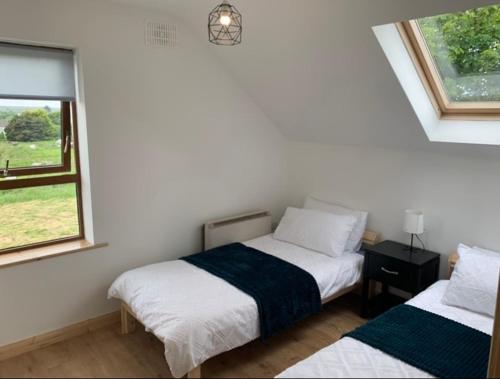 a bedroom with two beds and a window at Tigh na Mara, Brand New Semi-Detached House, Furbo in Furbo