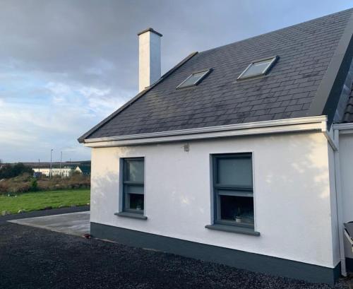 a white house with two windows and a roof at Tigh na Mara, Brand New Semi-Detached House, Furbo in Furbo