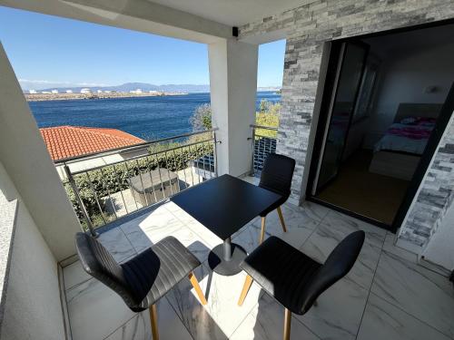 a balcony with a table and chairs and a view of the ocean at MERTIK house in Omišalj