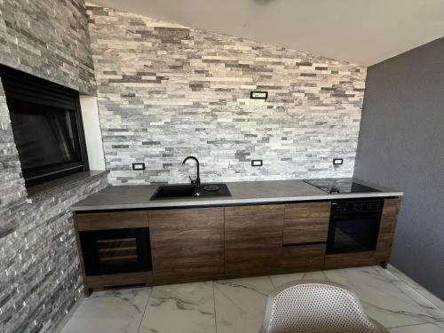 a kitchen with a sink and a brick wall at MERTIK house in Omišalj