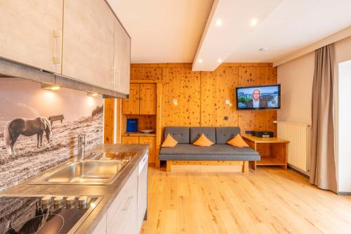 a kitchen with a couch and a tv on the wall at Ferienwohnung Ferienglück in Krün