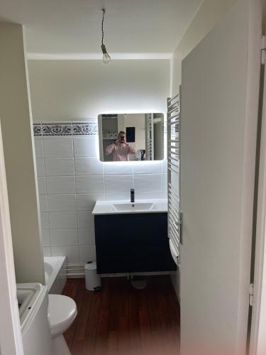 une salle de bains avec une personne prenant une photo dans le miroir dans l'établissement Appartement Vannes en résidence, à Vannes