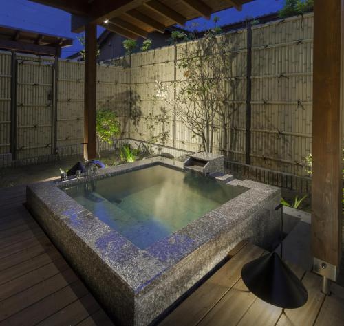 a jacuzzi tub in a backyard with a fence at Kizukuri no Yado Hashizuya in Misasa