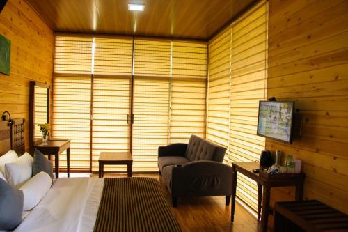 a bedroom with a bed and a chair and a television at EllaCrest by Aloft in Kumbalwela