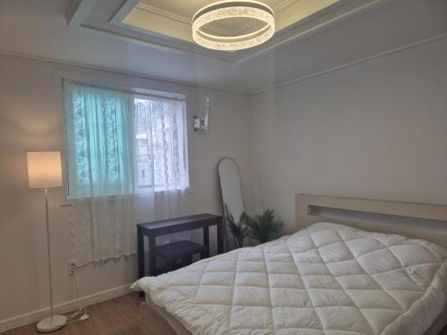 釜山にあるSmall and Pretty House Near Busan Station, Pet-friendly, Suitable for 2 Peopleの白いベッドと窓のある寝室