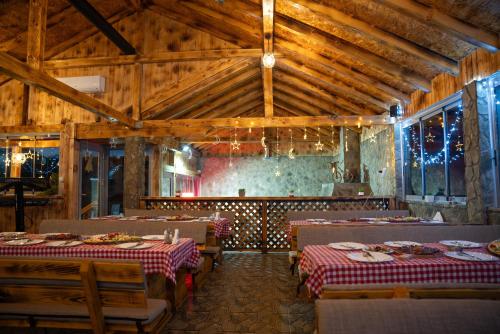 una sala da pranzo con tavoli, sedie e soffitti in legno di EJDE RESORT Šiljkovača a Velika Kladuša