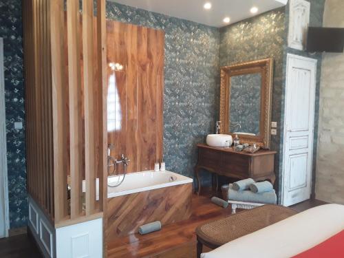 une salle de bain avec une baignoire, un lavabo et un miroir dans l'établissement manoir de la baronnie d'urville, à Urville