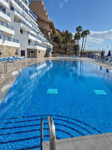 a large swimming pool in front of a building at Taurito Luxholidays ocean view in Taurito