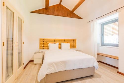 a white bedroom with a large bed and a window at Solar do Maranhão in Capelas