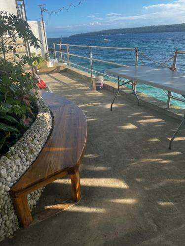 a wooden bench sitting on a dock next to the ocean at Villa Talisay - Beach house in Samal