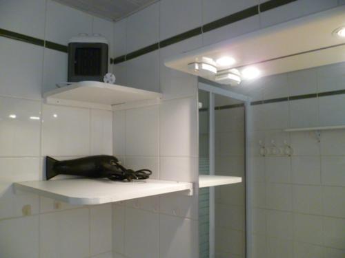 une salle de bains avec une étagère et une télévision. dans l'établissement Studio cosy avec terrasse privée, à Montferrier