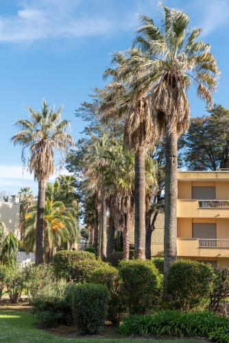 a group of palm trees in front of a building at Les 15 Pins & La Mer -Your green getaway near sea & beach in Antibes