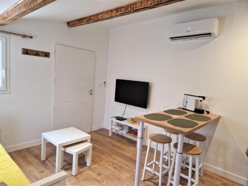 a living room with a table and a tv at Emeric & Julie Lou Pescalune classé 3 étoiles in Lunel