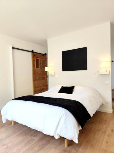 - une chambre blanche avec un grand lit et une télévision murale dans l'établissement Magnifique gîte écologique en pleine campagne avec piscine, à Pont-du-Casse