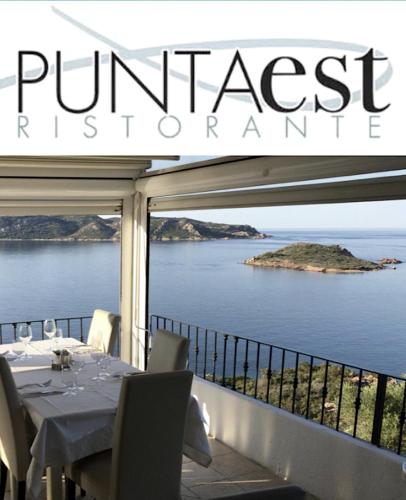 a dining table on a balcony with a view of a island at Trilocale PUNTA EST Vista Mare in Capo Coda Cavallo
