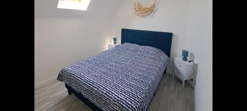 a bed with a blue comforter in a bedroom at Appartement avec une place de parking in Fécamp