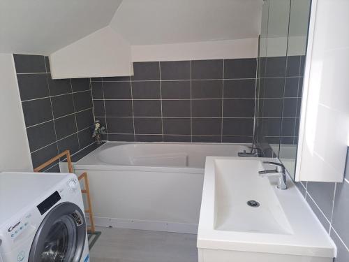 a bathroom with a sink and a washing machine at Appartement avec une place de parking in Fécamp