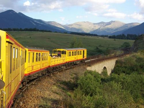 a yellow train traveling over a bridge over a field at Evasions catalanes - confort vue et grand air in Saillagouse