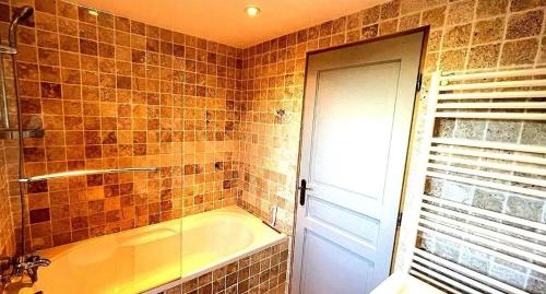 La salle de bains carrelée est pourvue d'une baignoire et d'une fenêtre. dans l'établissement Le Beau Coin, à Serviès-en-Val