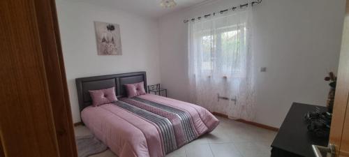 - une chambre avec un lit avec des draps roses et une fenêtre dans l'établissement Madureira Country House - Natureza & Tranquilidade, à Paradela de Guiães