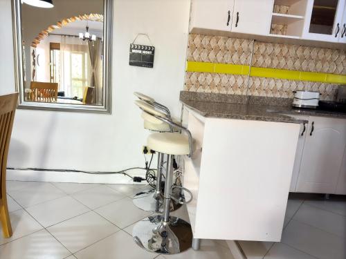 a kitchen with a white counter and a stool at JM Furnished Kampala Entebbe Rd B in Lubowa