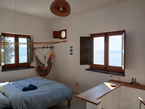 a bedroom with a bed and a desk and windows at Casa al Vallone in Alicudi