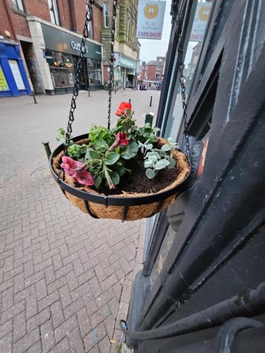 a hanging planter with flowers hanging from a building at Central Chambers Suites Suite 3 in Leek