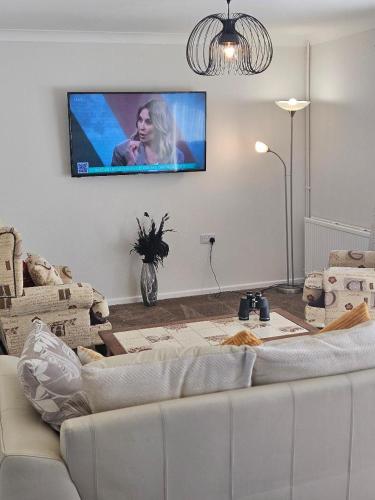 a living room with a couch and a tv on the wall at Greenways at Coed Cae Farm in Pontnewydd