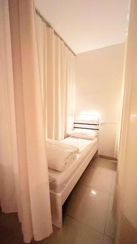 a small white room with a bed and curtains at WeStay Ladies Hostel in Dubai