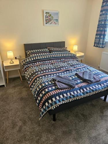 a bed with a quilt on it in a bedroom at Greenways at Coed Cae Farm in Pontnewydd