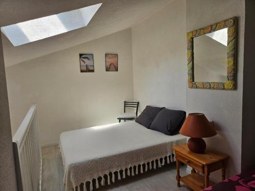 a bedroom with a bed and a table with a lamp at Bel appartement climatisé vu sur l'étang in Leucate-Plage