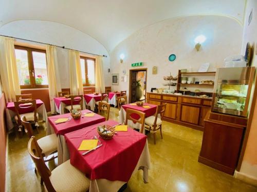 un restaurante con mesas y sillas rojas y una cocina en Hotel Villa Canu, en Cabras
