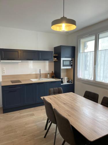 une cuisine avec des placards bleus et une table en bois dans l'établissement 3 min du parc du PUYDUFOU Centre des Epesses logement 4 à 6 personnes, L Ecrin du Puy, aux Épesses