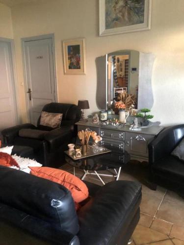 a living room with black leather furniture and a mirror at L'hôte de la chaussée de lille in Tournai