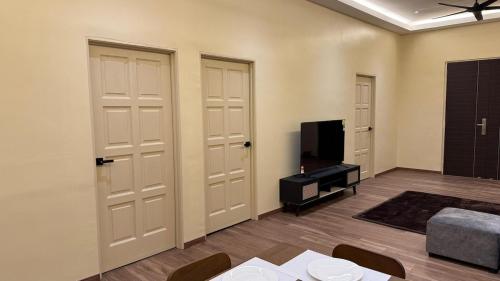a living room with two white doors and a tv at Cosy Nest Homestay with 60 inch 4K android TV in Muar
