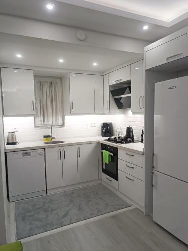 a white kitchen with white cabinets and a refrigerator at YoYo Apart in Dalaman
