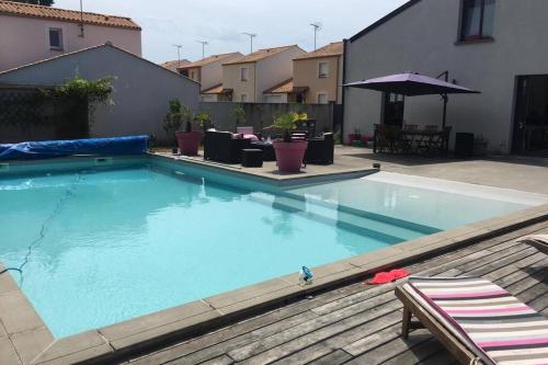 une grande piscine avec des chaises et un parasol dans l'établissement Maison loft piscine, à Le Fenouiller