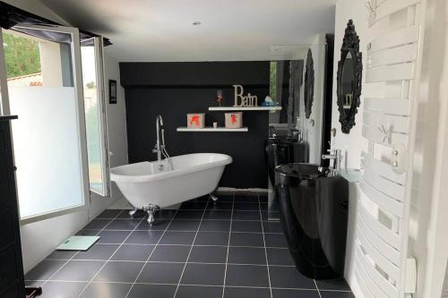 La salle de bains est pourvue d'une baignoire blanche et d'un mur noir. dans l'établissement Maison loft piscine, à Le Fenouiller