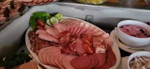 a plate of meats and vegetables on a counter at Hotel garni SEESCHLÖSSCHEN in Kolpinsee