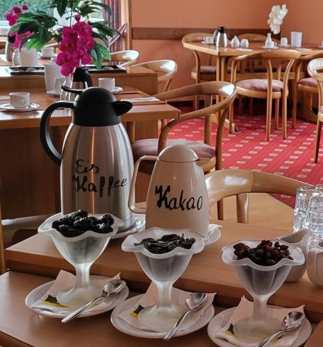 a tea kettle and saucers on a table in a restaurant at Hotel garni SEESCHLÖSSCHEN in Kolpinsee
