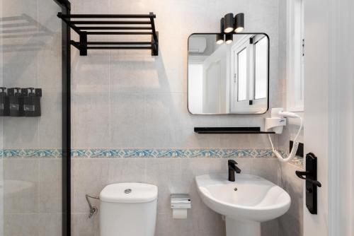 Un baño con inodoro, lavabo y espejo. en Casco antiguo terraza y vistas al mar Playa a Pie 1B, en Nerja