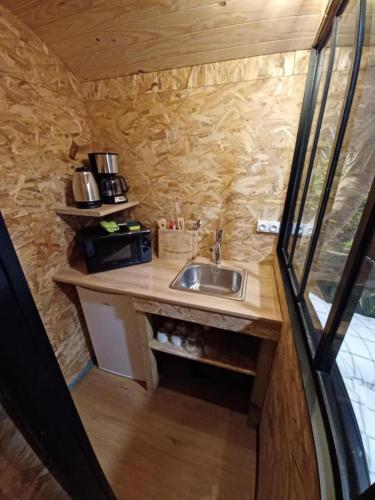 une cuisine avec un évier dans une petite maison dans l'établissement Roulotte de Camille, avec bain à remous, à Winnezeele