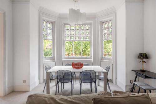 a white dining room with a table and chairs at Casa Italia near Sloane Square, Harrods and Kings Road - Washing Machine & Wifi in London